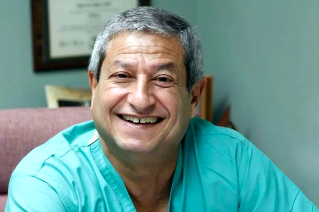 The photo shows Dr. Matar Nabil in a medical gown, which is standing in the office, behind him you can see medical equipment and shelves with medicines