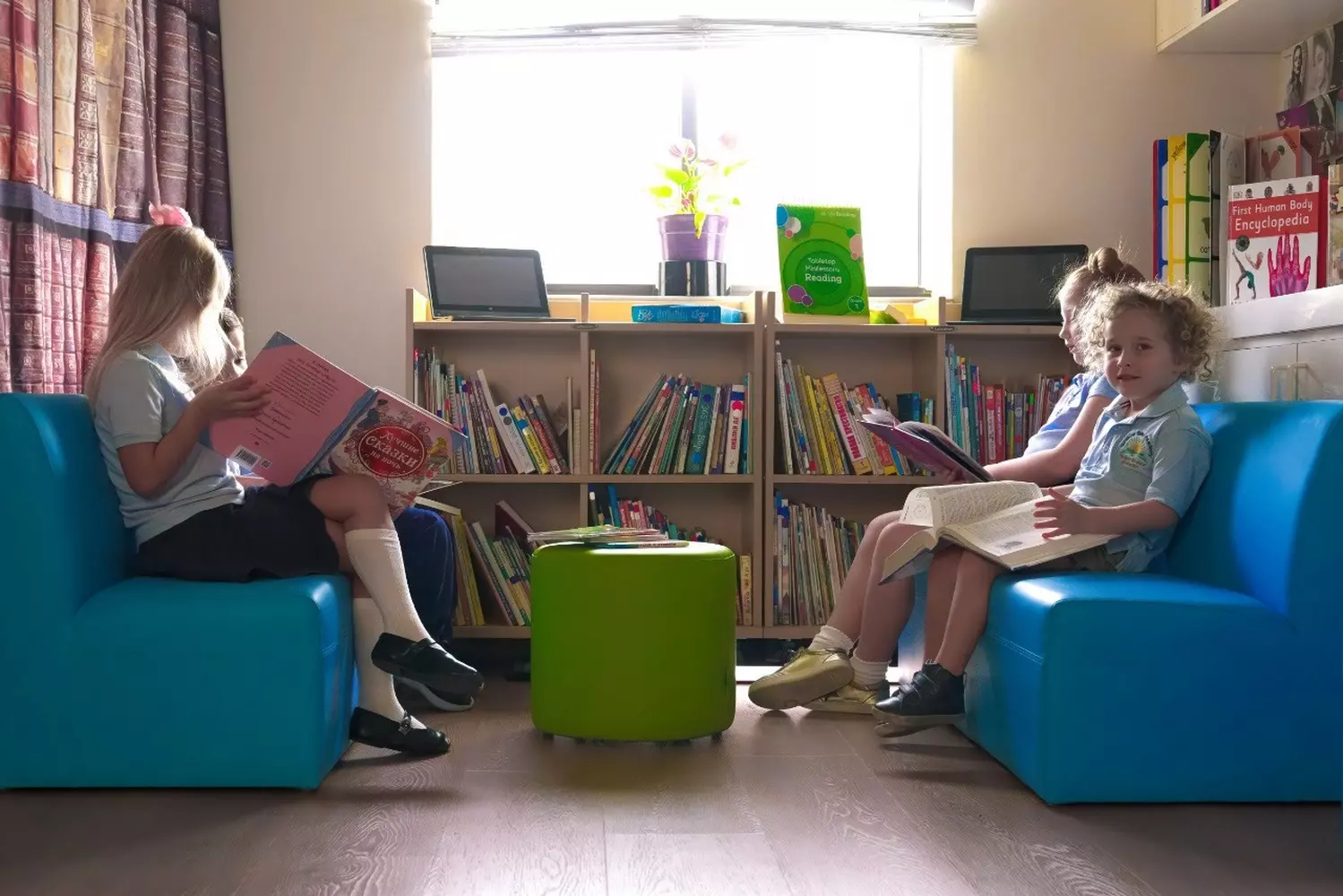 Children's Library at Sunshine State Academy Preschool in Miami Preschool children sitting in the bright, colorful library at Sunshine State Academy in Miami, looking at picture books with a teacher