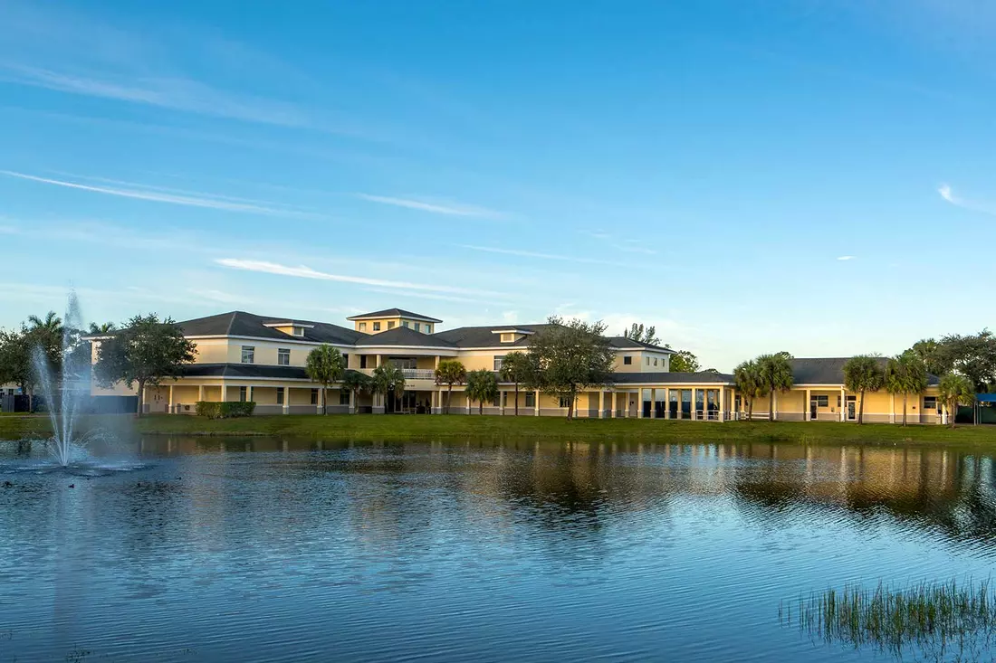 Озеро с фонтаном на фоне школьных зданий North Broward Preparatory School — American Butler