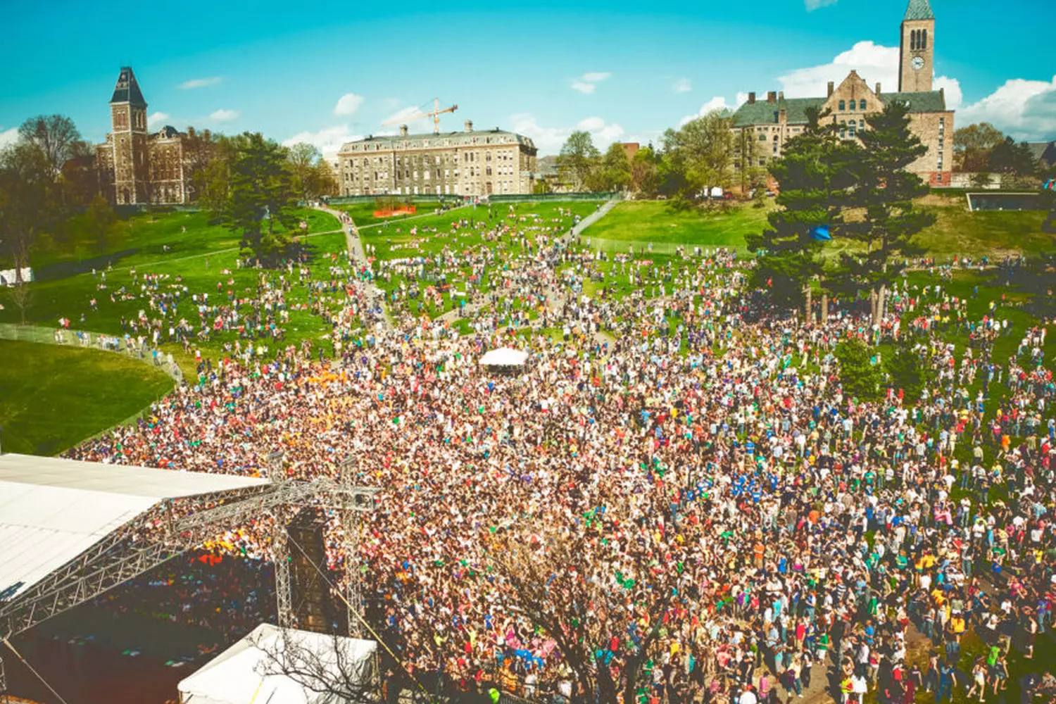 Общий вид музыкального фестиваля Slope Day в Корнеллском университете: множество студентов на склоне Лайб слушают живую музыку на фоне знаменитой часовой башни кампуса
