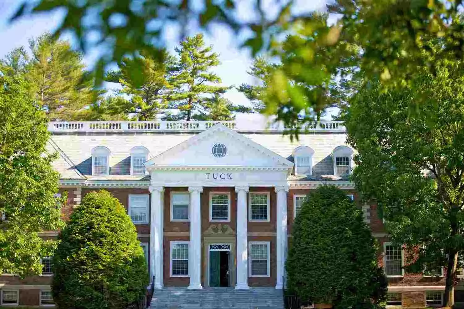 Ворота к лидерству: Школа бизнеса Дартмута Современный фасад из стекла и стали Школы бизнеса Така в Дартмуте, студенты работают вместе в просторных лобби