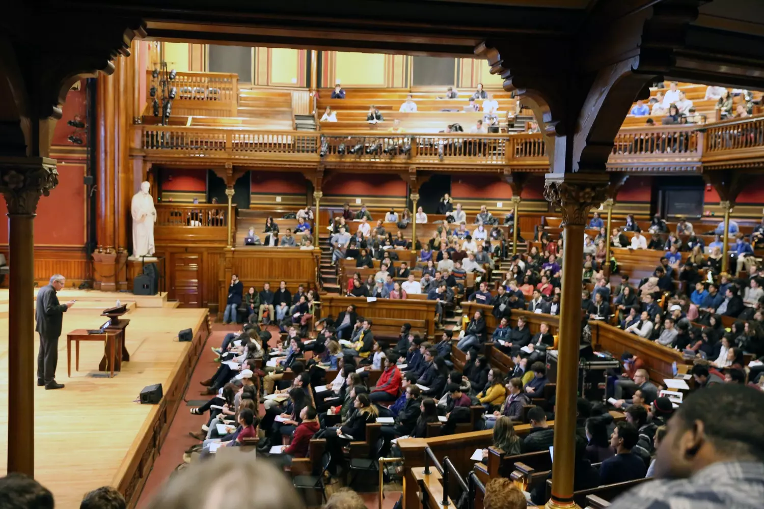 Просторная амфитеатрная аудитория в Гарварде с деревянными партами, уходящими рядами вверх