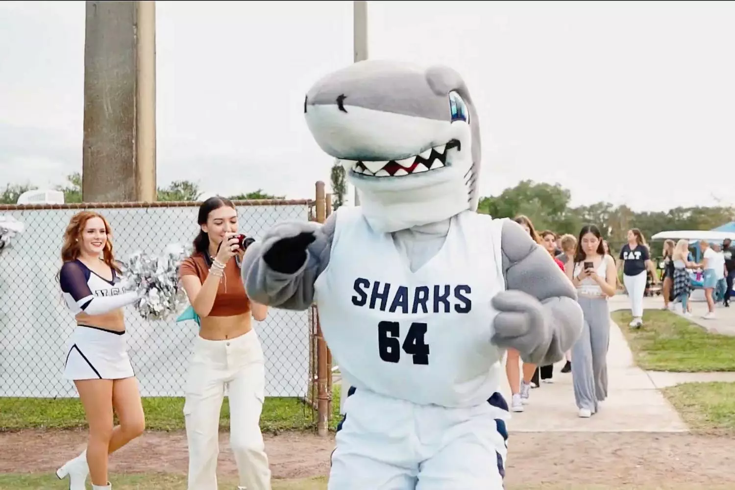 NSU Mascot Interacting with Students at University Event The Nova Southeastern University mascot in a full-body costume smiling and posing with students on campus during a university celebration