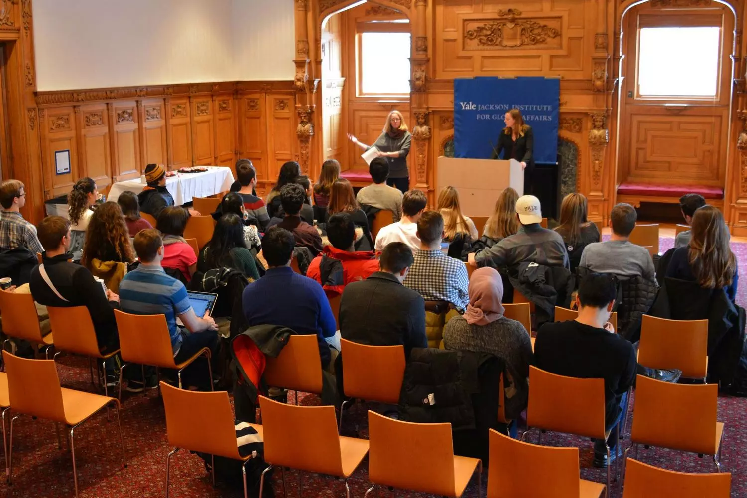 Legendary Yale Lecture Hall: Where Great Ideas Are Born A spacious academic lecture hall at Yale University with wooden benches, amphitheater seating, and a large blackboard