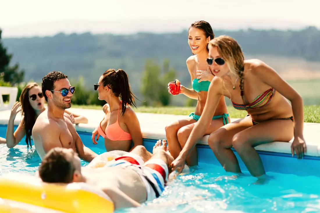 A group of people enjoy an evening at a private pool party in Miami. The blue sky is visible in the background, creating a unique atmosphere for the celebration.