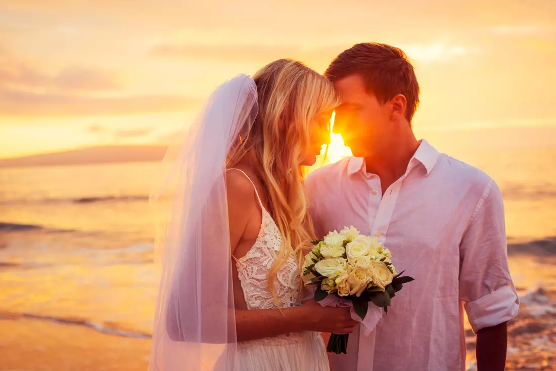 The picture shows the newlyweds standing on the beach in Miami and kissing into the sunset. Beautiful ocean views and luxurious decor create an atmosphere of romance and celebration