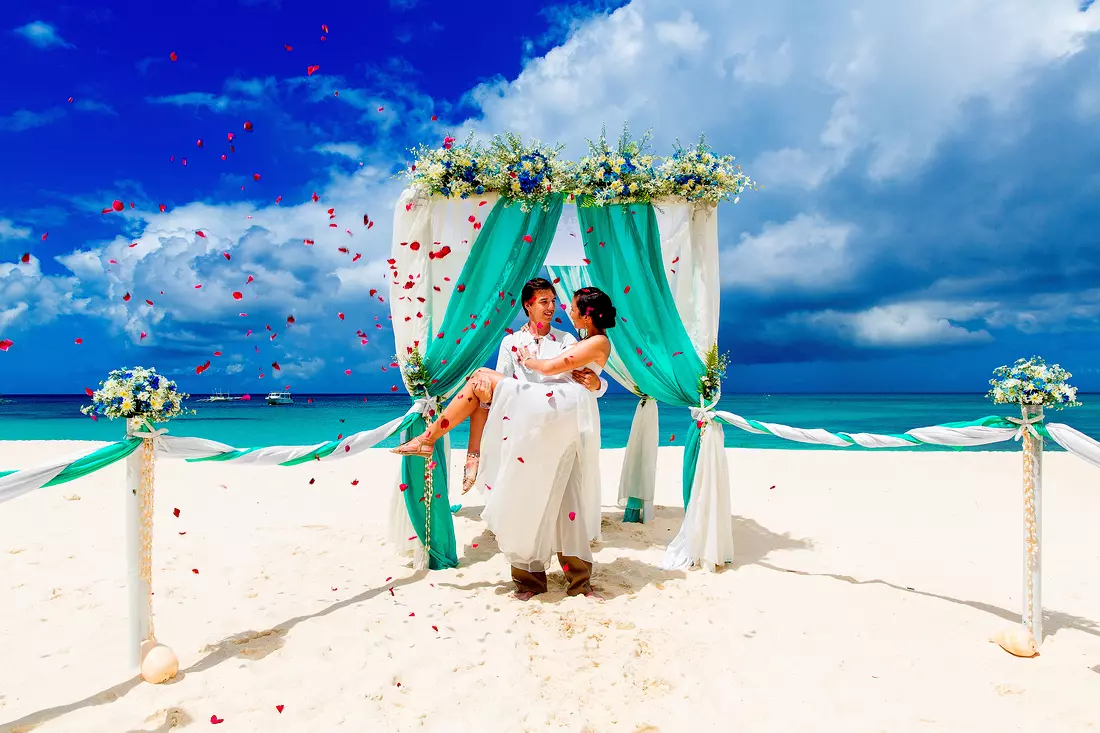 The picture shows a ceremony at a wedding in Miami on the beach. A light breeze and the murmur of waves create a peaceful atmosphere on the ocean, which will help create an atmosphere of celebration