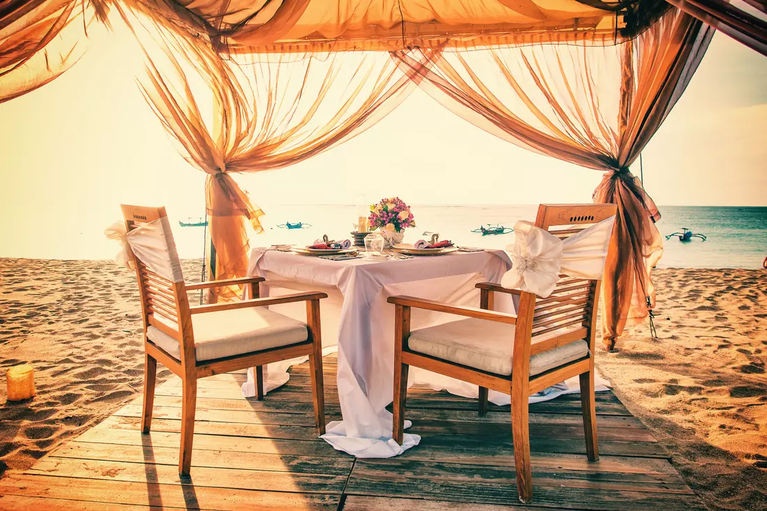 The picture shows a beautifully decorated table at a Miami beach wedding. Picturesque ocean views, soft sand and a cozy corner create an atmosphere of romance and celebration