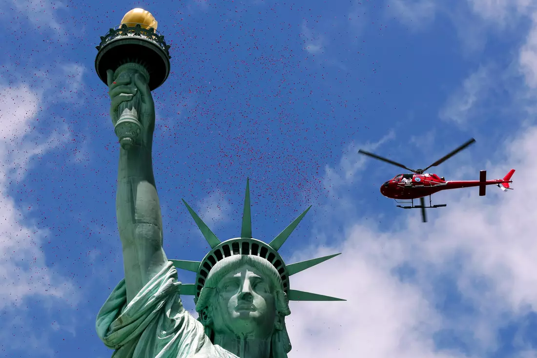 Photo of a helicopter in the sky above the Statue of Liberty in New York