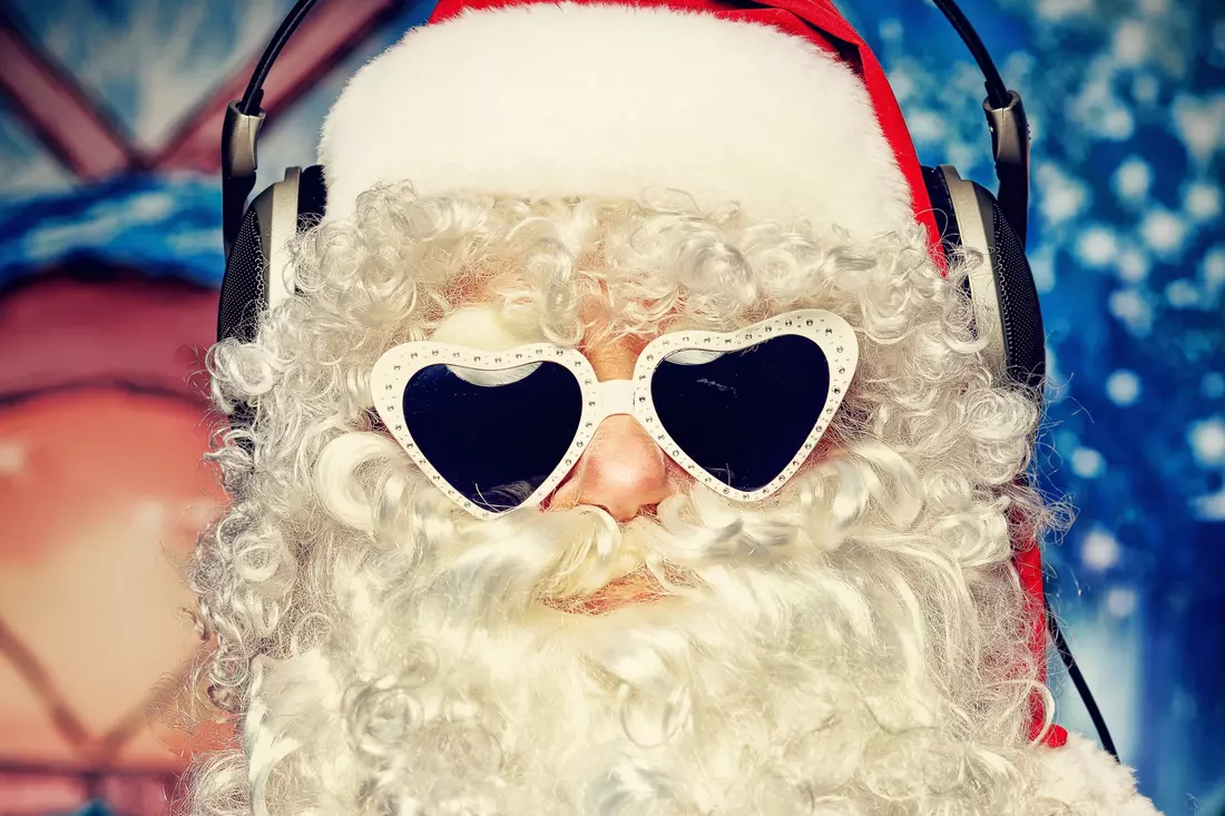 Santa Claus wearing white heart-shaped sunglasses against a winter backdrop