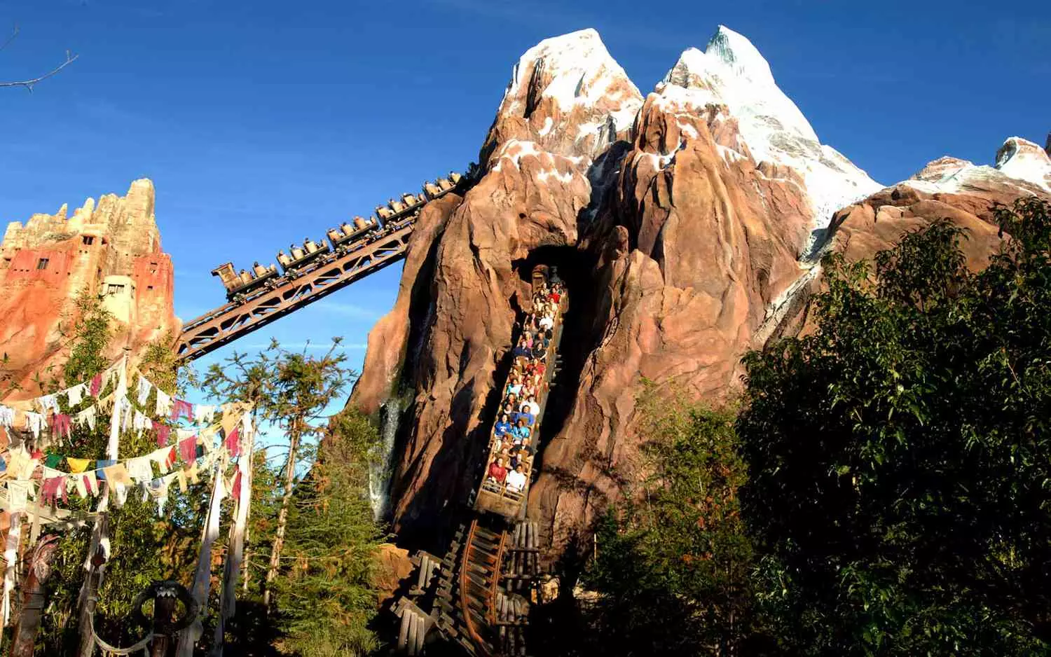 The "Expedition Everest" attraction in Animal Kingdom — an icy extreme adventure he "Expedition Everest" roller coaster shaped like a snow-covered Himalayan mountain, with twisted tracks and a figure of the Yeti, against the backdrop of screaming visitors