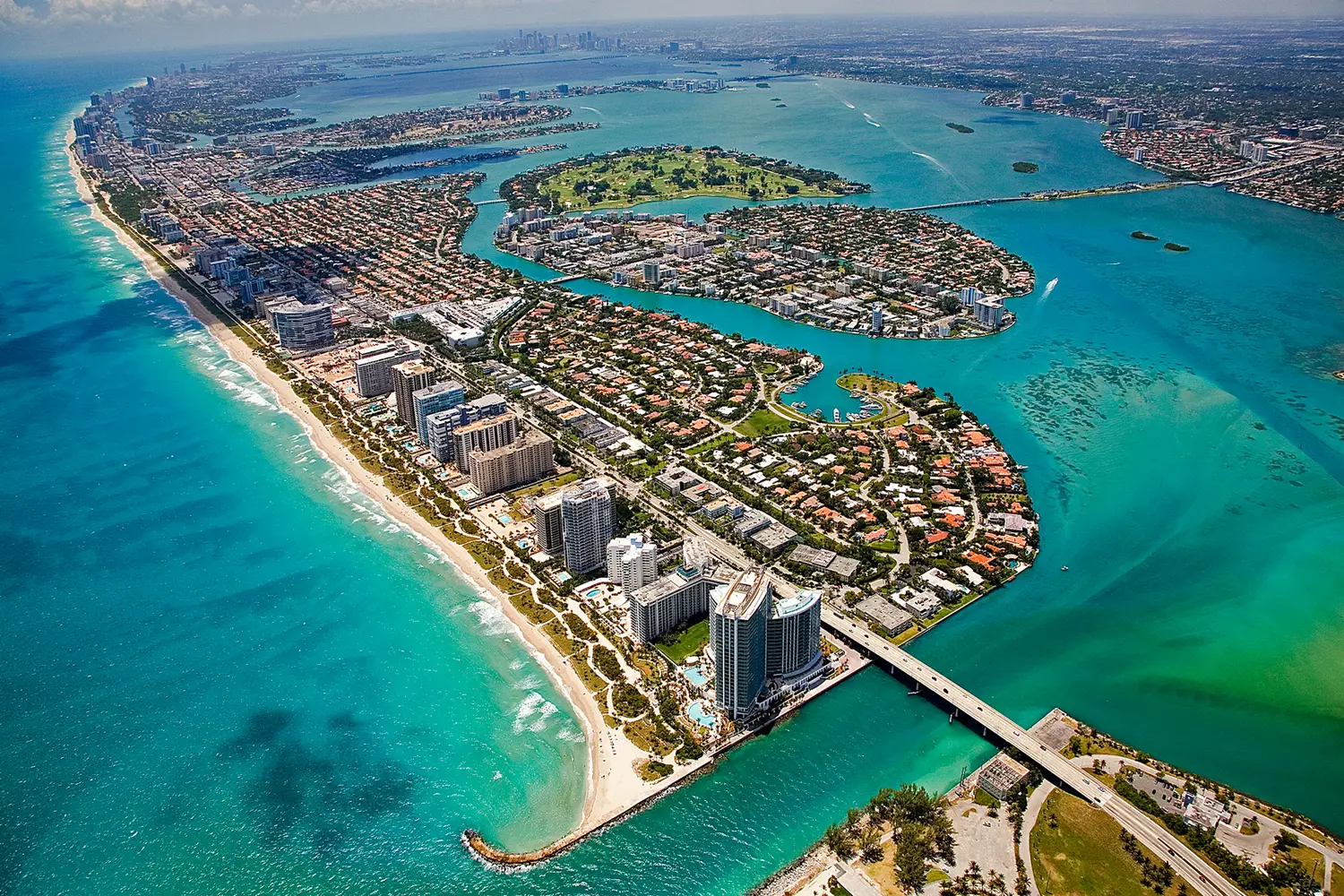 Aerial helicopter view of the Miami islands featuring luxury mansions against turquoise Biscayne Bay waters and the Downtown skyline