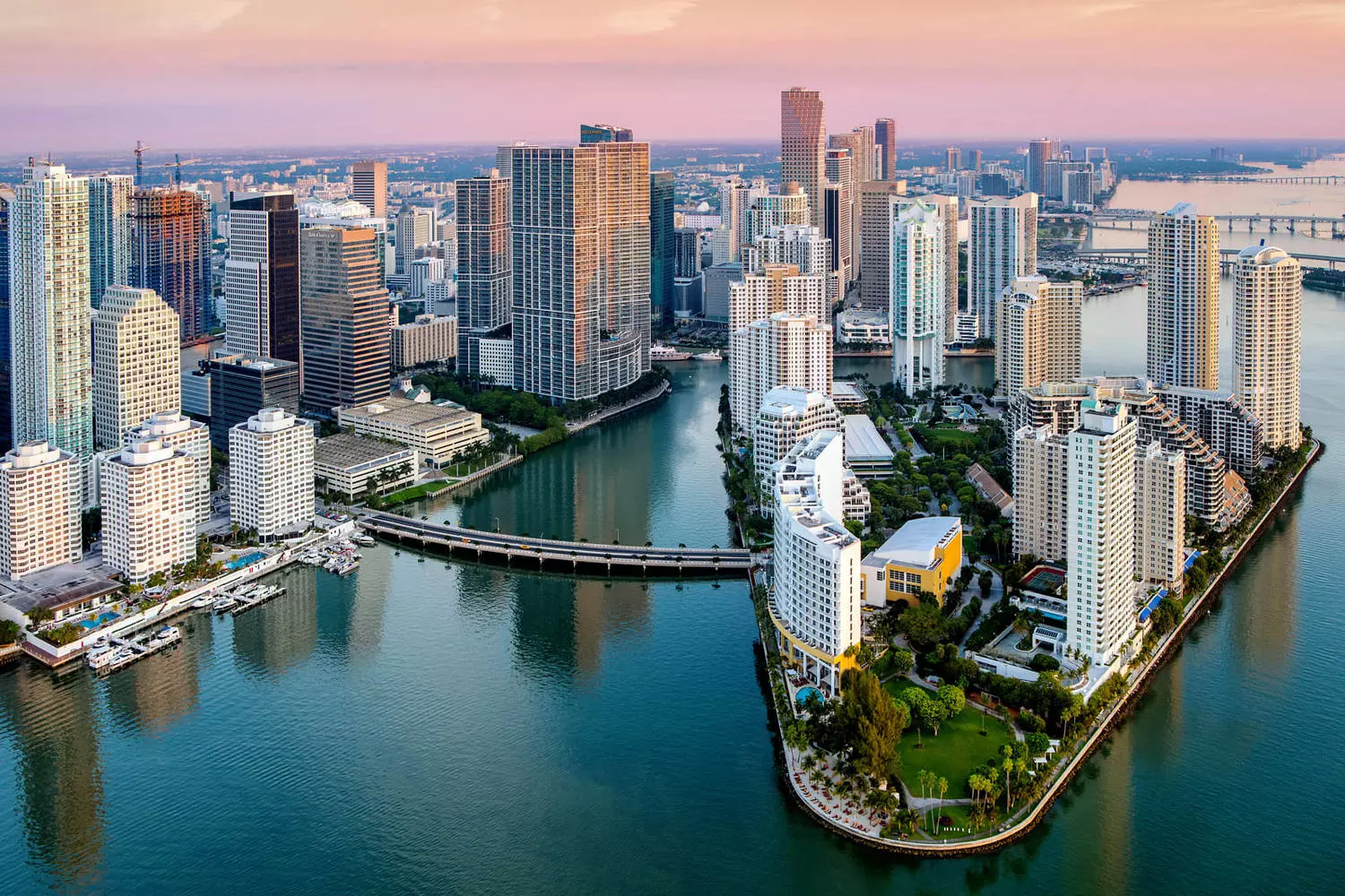 Aerial helicopter view of Miami featuring modern Downtown skyscrapers and winding canals with yachts, overlooking Biscayne Bay