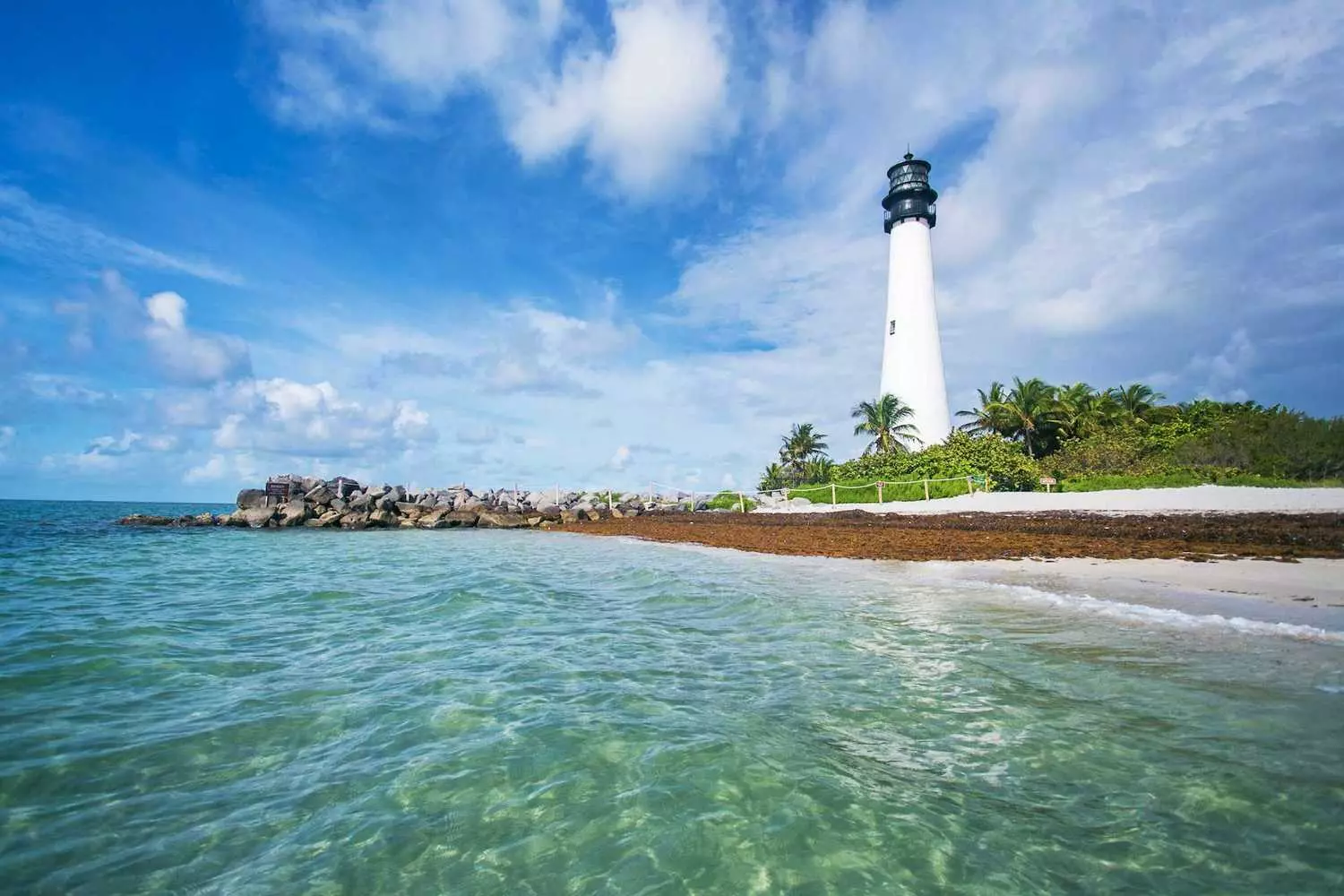 Key Biscayne Lighthouse — Historic Beacon Overlooking Miami's Turquoise Waters The iconic red-and-white Key Biscayne Lighthouse standing against blue skies, with panoramic ocean views and lush greenery surrounding this historic coastal landmark