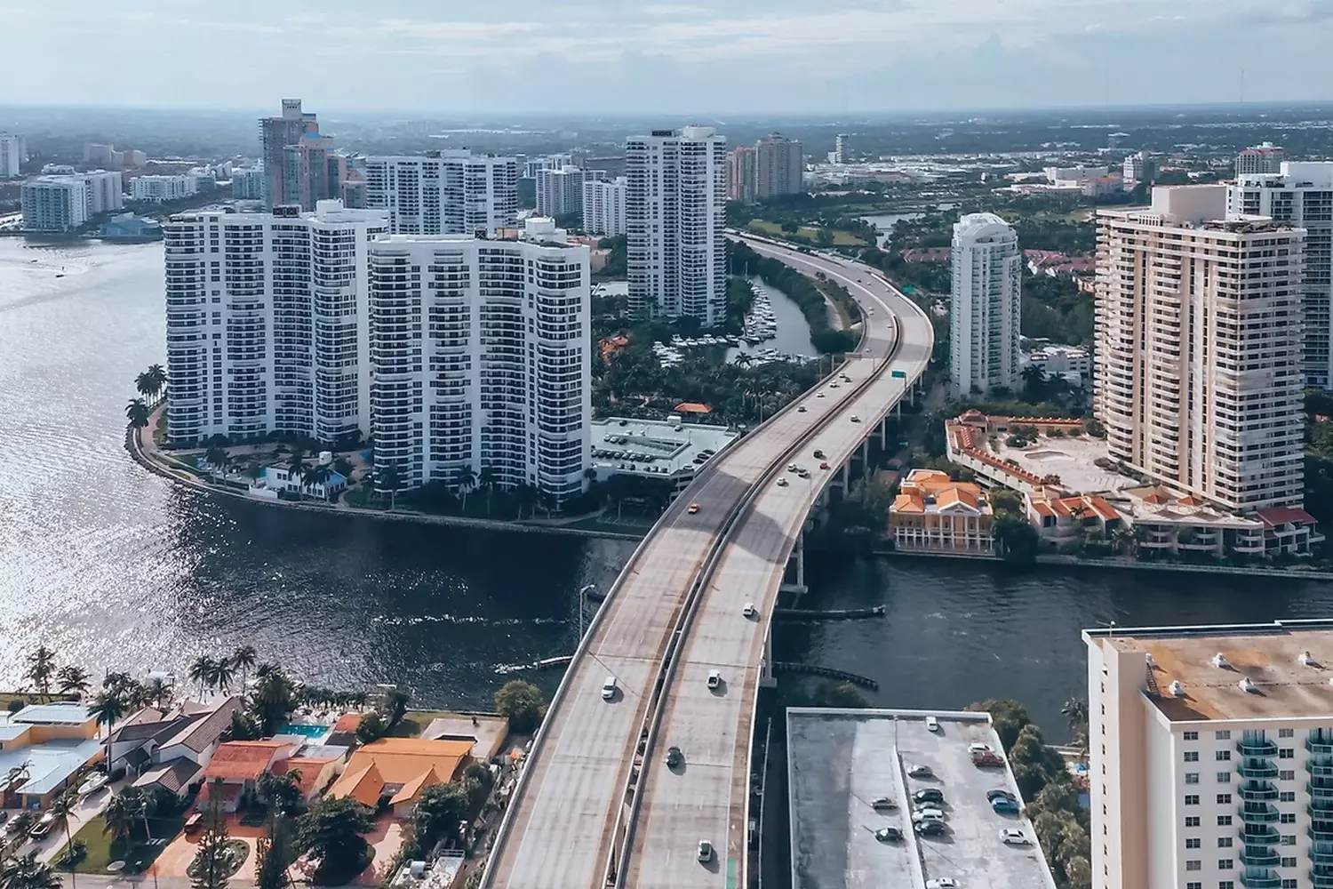Helicopter aerial view of the Florida coastline with skyscrapers, a highway bridge, and the Atlantic Ocean from a bird's eye perspective