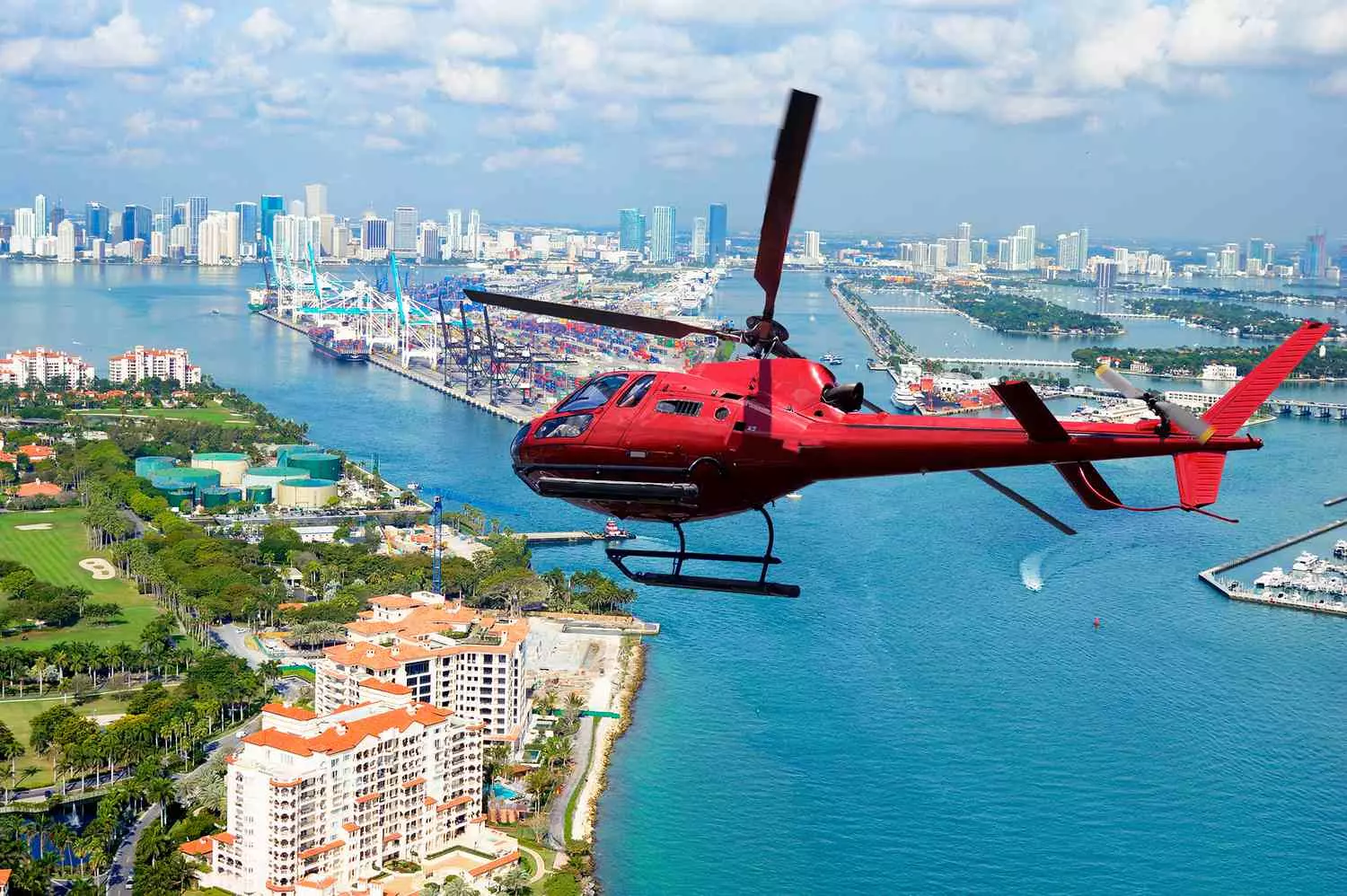 Helicopter Soaring Over Miami — Aerial View of the Coastline A helicopter flying over the sunny skies of Miami with the ocean and cityscape in the background