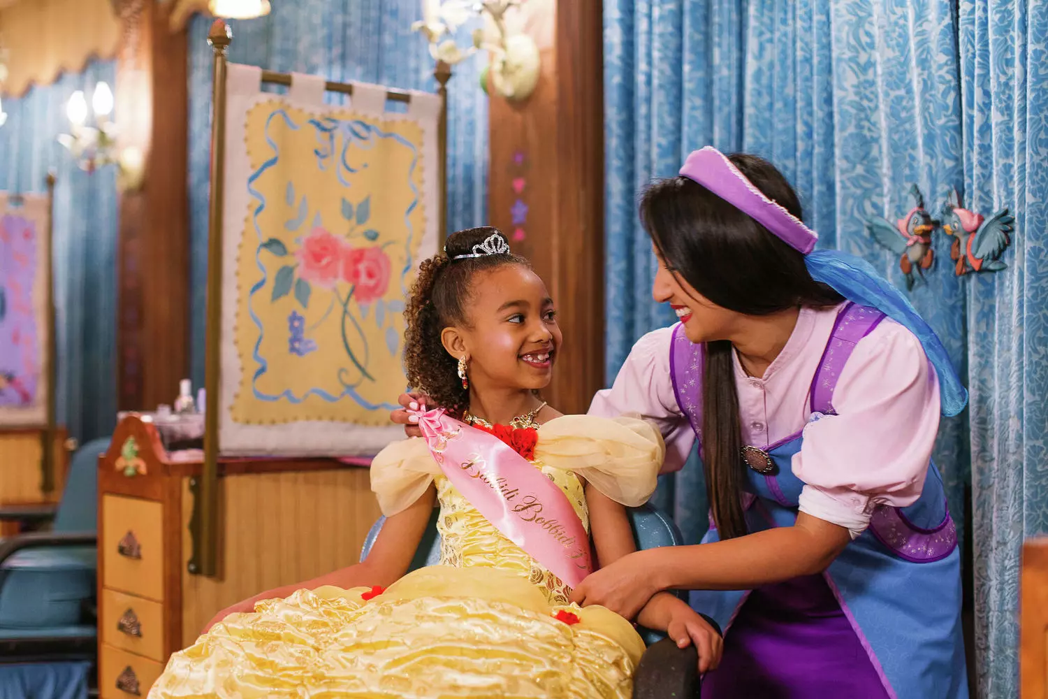 Волшебные превращения в Bibbidi Bobbidi Boutique в Диснейленде Орландо Девочка в костюме принцессы Disney делает прическу у крестной феи в салоне Bibbidi Bobbidi Boutique в Magic Kingdom, Орландо, на фоне сверкающих зеркал и волшебного декора