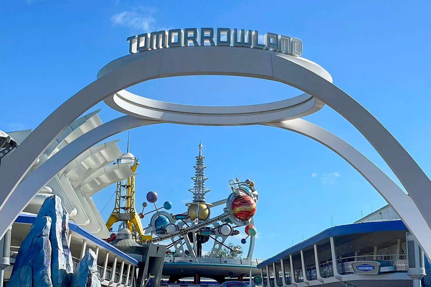 Футуристические приключения в Tomorrowland в Диснейленде Орландо Футуристическая архитектура Tomorrowland в Magic Kingdom Орландо: знаменитые американские горки Space Mountain и неоновая подсветка на фоне голубого неба, посетители исследуют зону в стиле научной фантастики