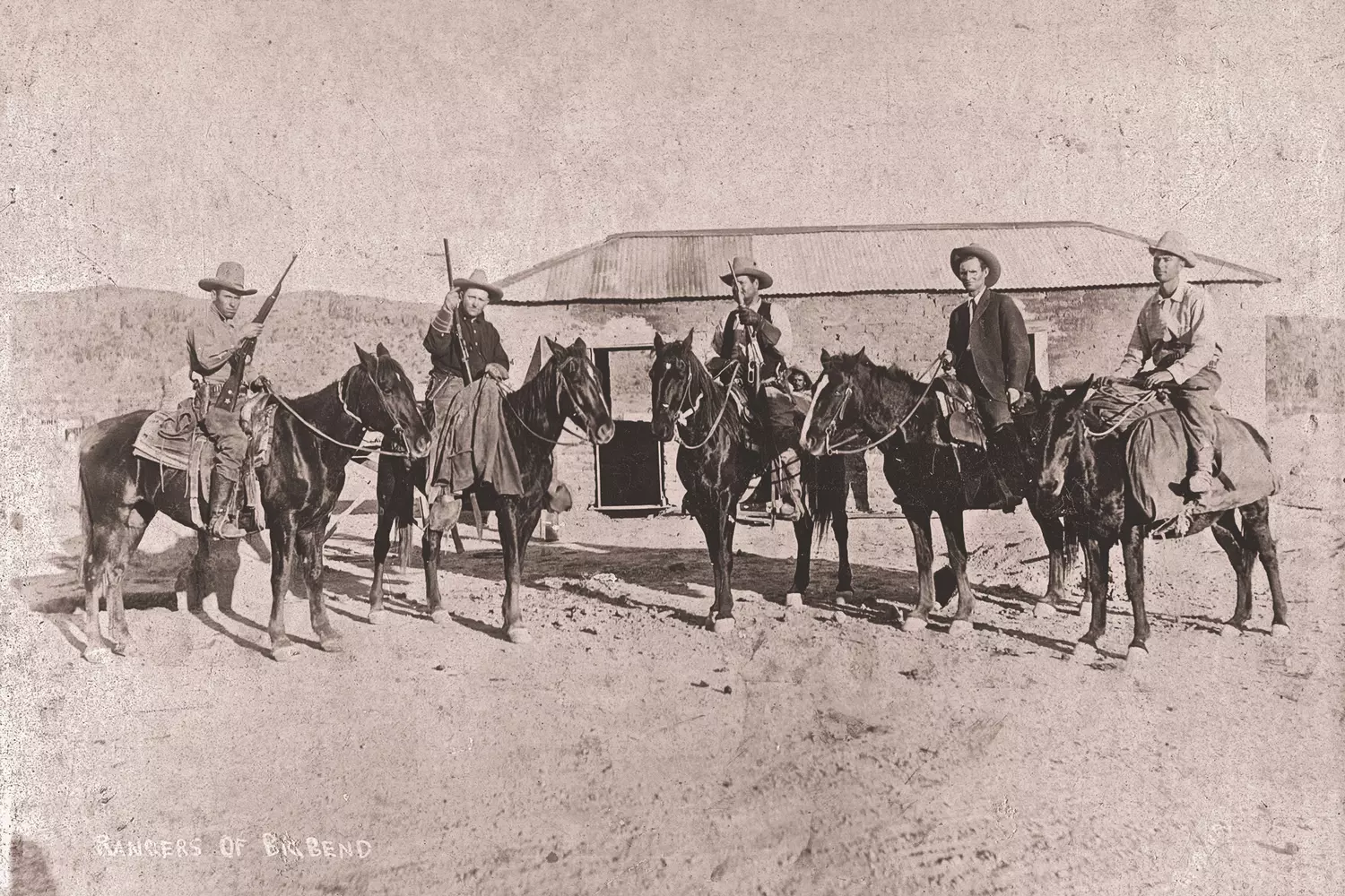 Legends of the Lone Star: Rare Historical Photo of Texas Rangers in Action "A vintage black-and-white photograph of Texas Rangers, dressed in classic cowboy attire, standing solemnly with their firearms — a powerful glimpse into the frontier law enforcement of the 19th century