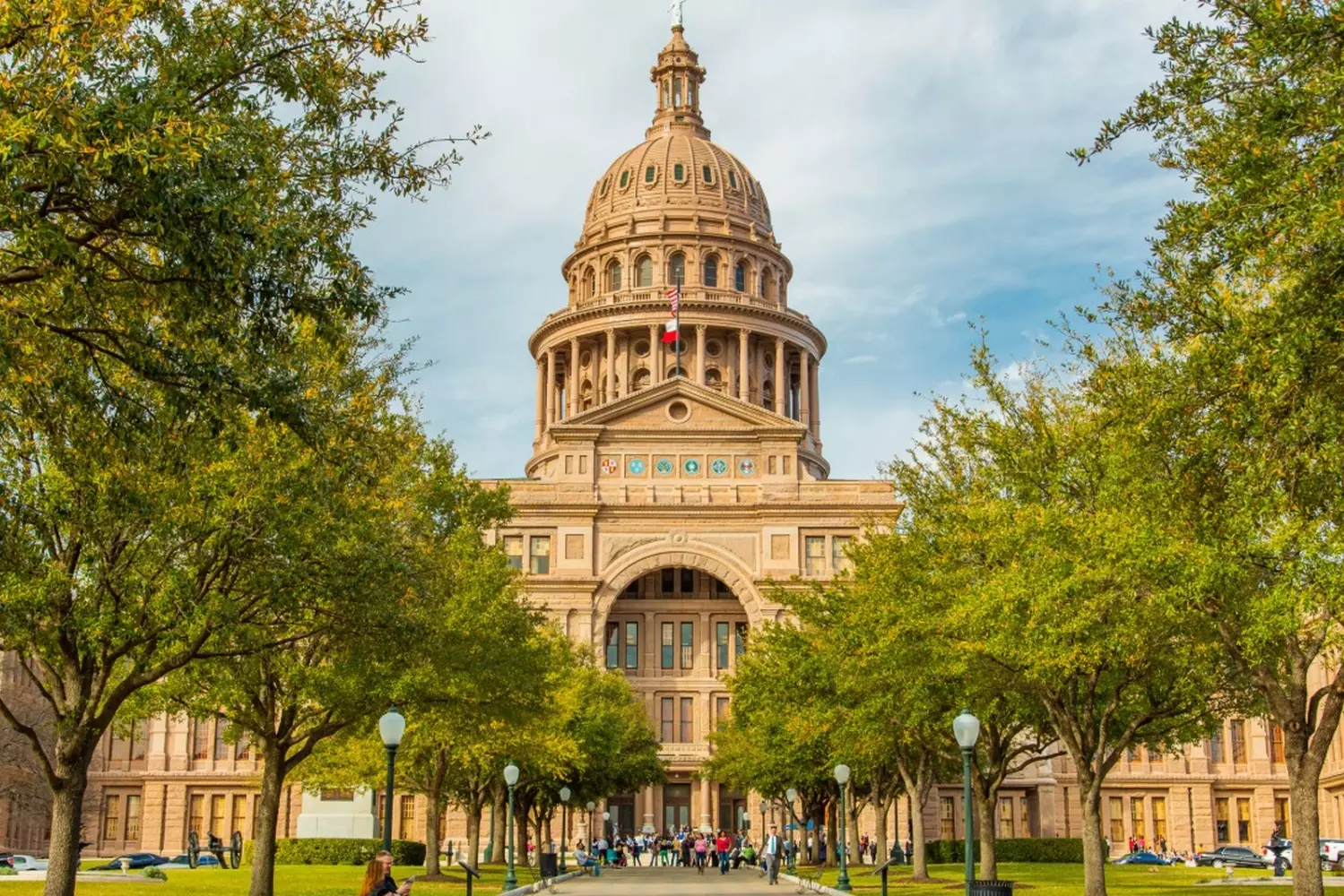 The Lone Star's Crown Jewel: Texas State Capitol in All Its Glory Majestic Texas State Capitol building in Austin with its distinctive sunset-red granite facade, towering dome, and lush green grounds under clear blue skies