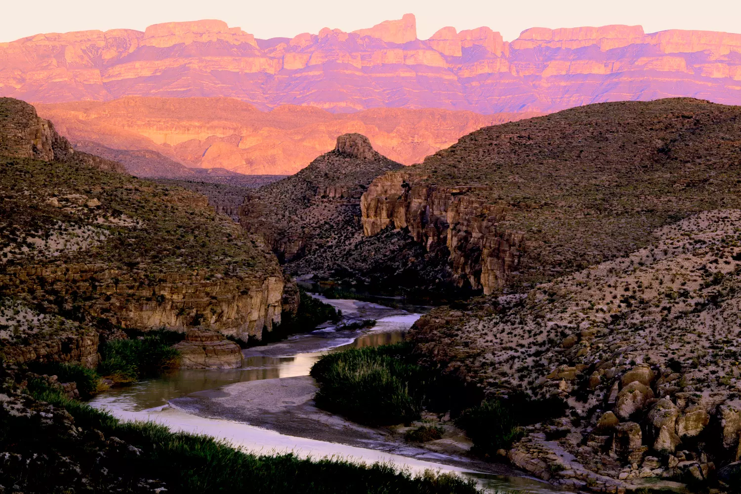 Big Bend Majesty: Where Desert, River and Mountains Collide Panoramic view of Big Bend National Park showcasing the Chisos Mountains, winding Rio Grande river, and vast Chihuahuan Desert under dramatic sunset skies
