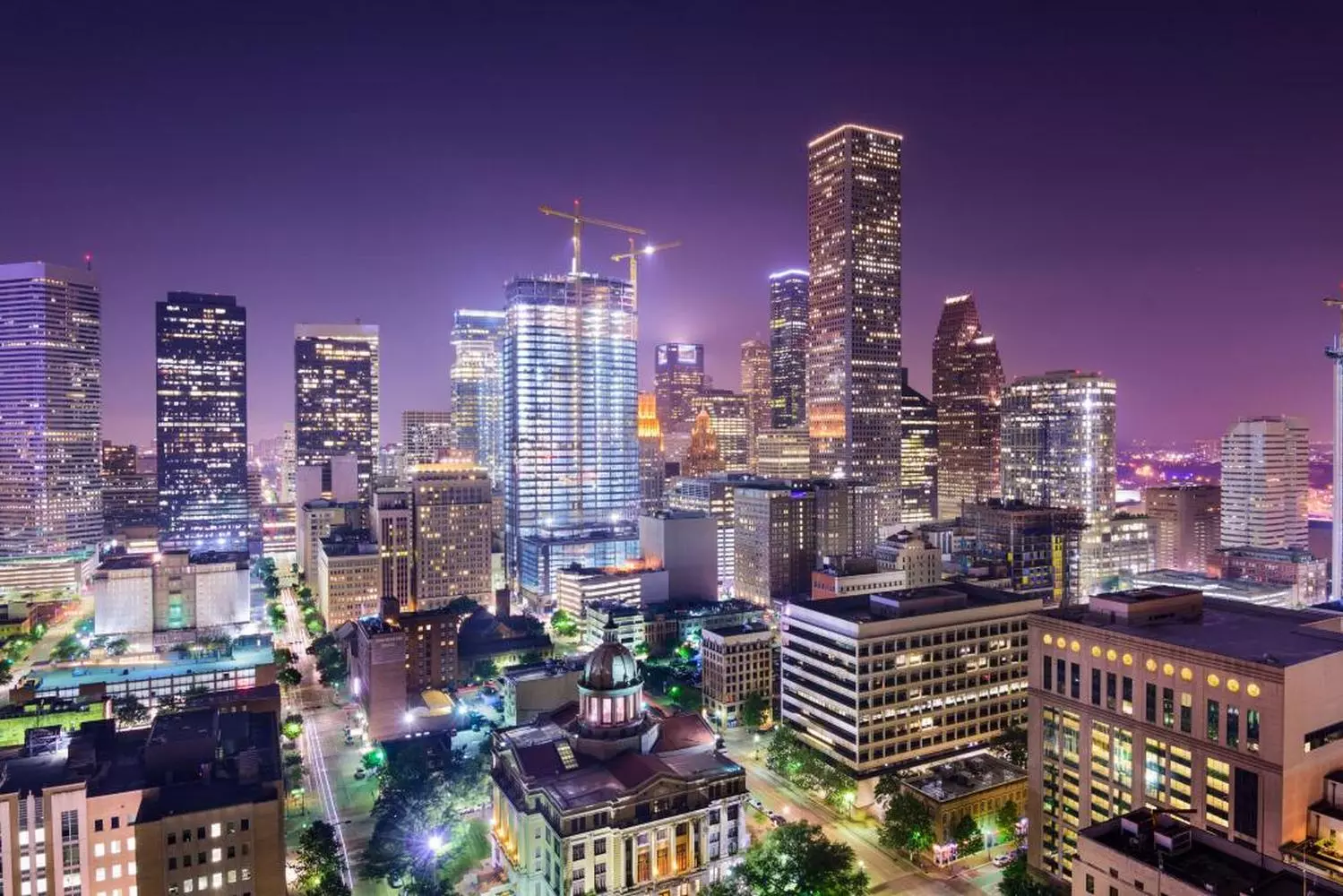 Houston Nights: Where the City Lights Meet the Stars A breathtaking night view of Houston's skyline, with towering skyscrapers illuminated against the dark Texas sky, reflecting in the calm waters below