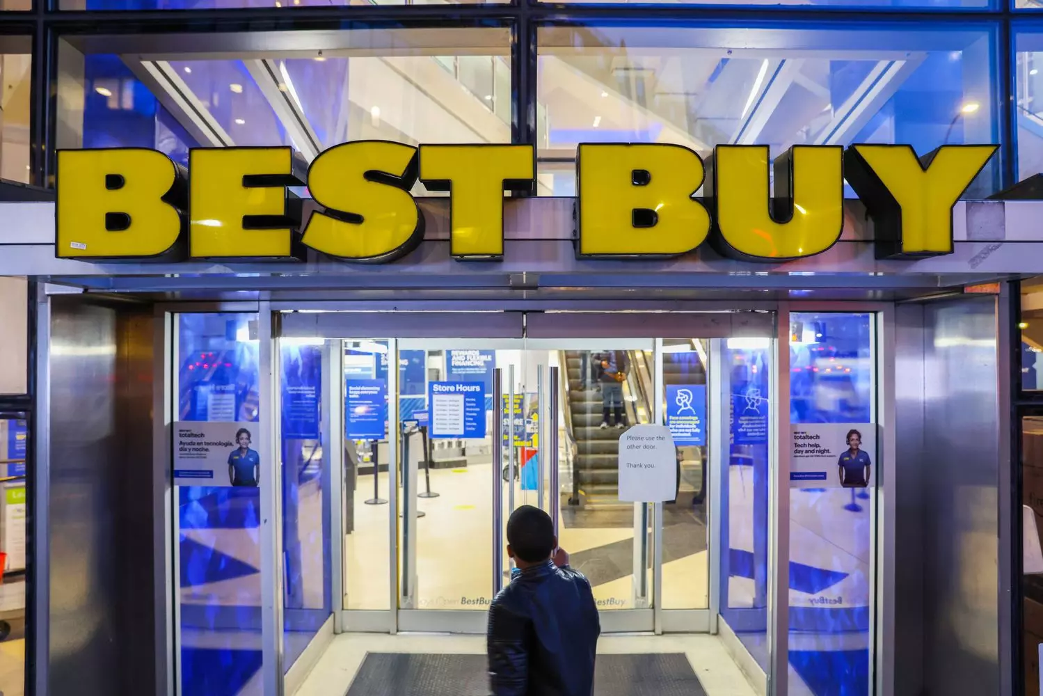 Главный вход в магазин Best Buy с большой синей вывеской и желтым ценником