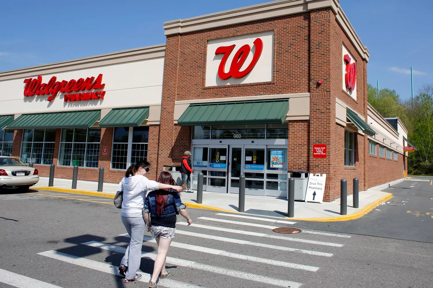 Walgreens store front with people walking into the parking lot