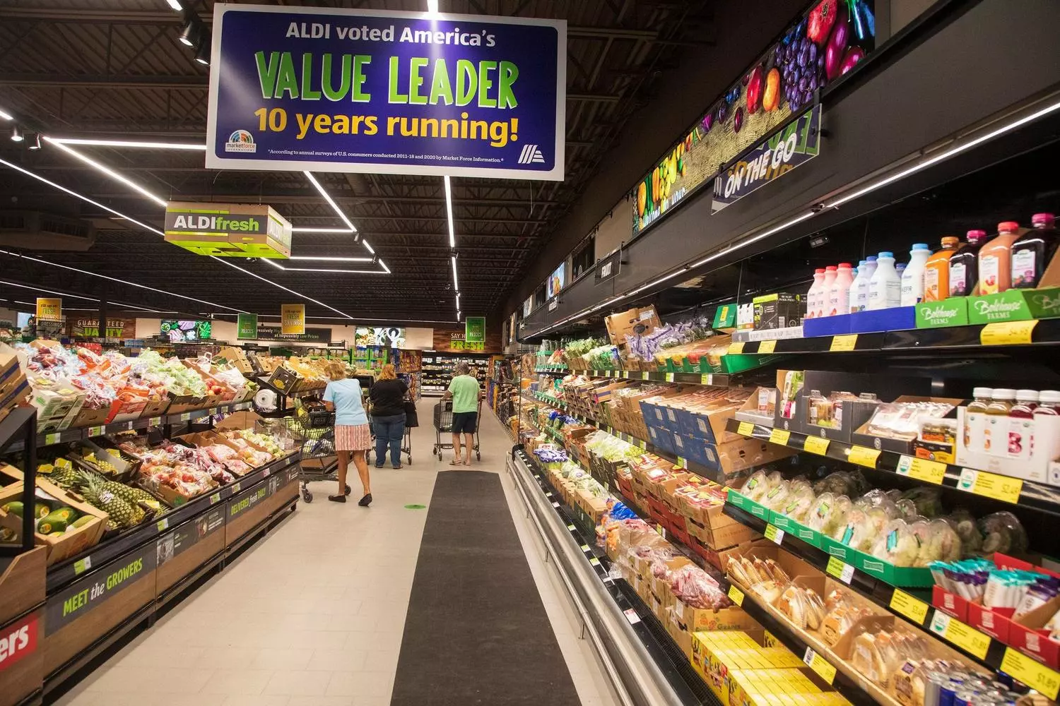 Inside ALDI USA: Smart Shopping in a No-Frills Environment Clean and efficient interior of an ALDI supermarket in the USA showing neatly organized shelves with private label products, shoppers with quarter-operated carts, and the store's signature minimalist layout under bright lighting