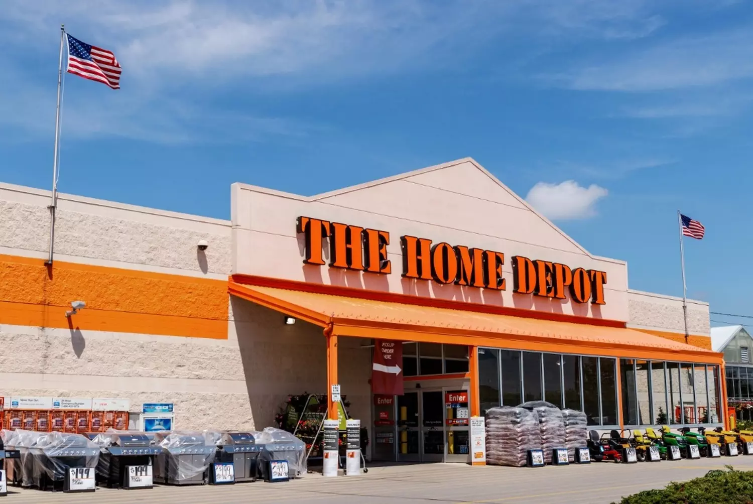 Home Depot USA: Iconic Exterior of America's Favorite Home Improvement Store Front view of a Home Depot store featuring the signature orange facade, large warehouse-style building with garden center, and shoppers loading purchases into their vehicles in the spacious parking lot