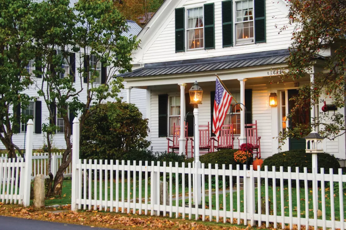 Traditional house with a fence and flag — symbols of the American Dream