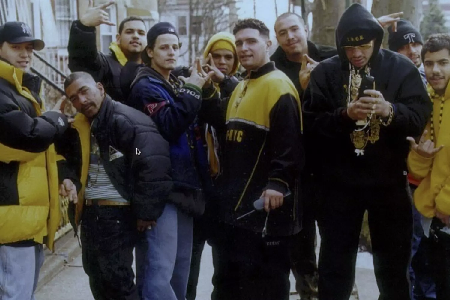 Короны улиц: Члены банды Latin Kings в США Участники банды Latin Kings позируют вместе, демонстрируя характерные жесты в форме корон и черно-золотые цвета одежды