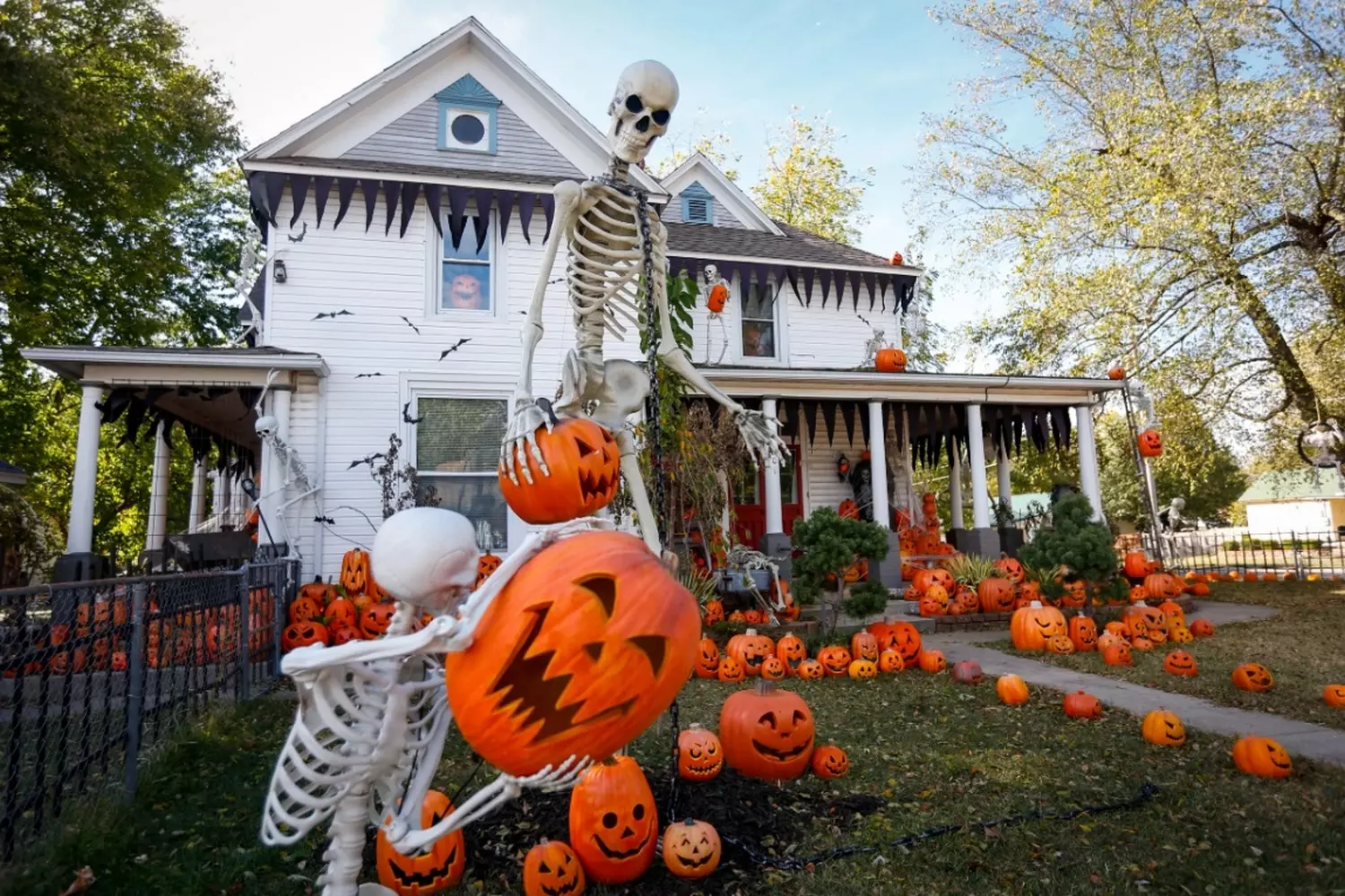 Ultimate Halloween House: Spooktacular Decorations & Lights A lavishly decorated house for Halloween with orange lights, giant spiders, cobwebs, jack-o'-lanterns, and spooky silhouettes in the windows, creating a festive haunted atmosphere