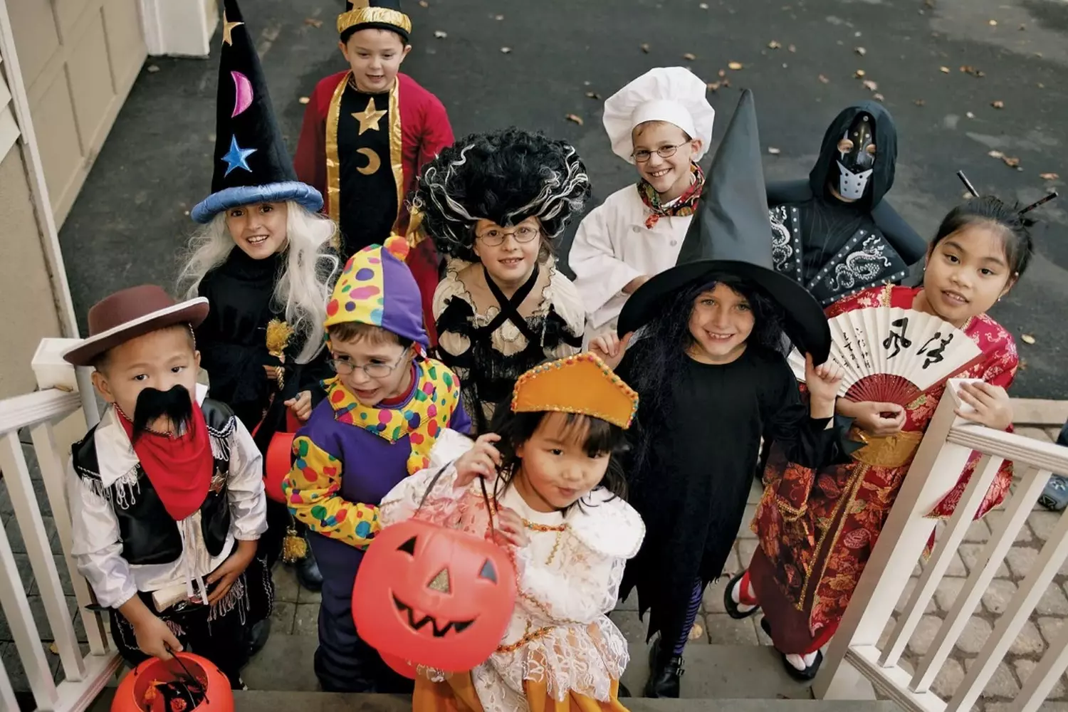 Spooky & Sweet: Kids Ready for Halloween Night Group of children in colorful Halloween costumes holding pumpkin buckets, smiling and posing together on a festive autumn night