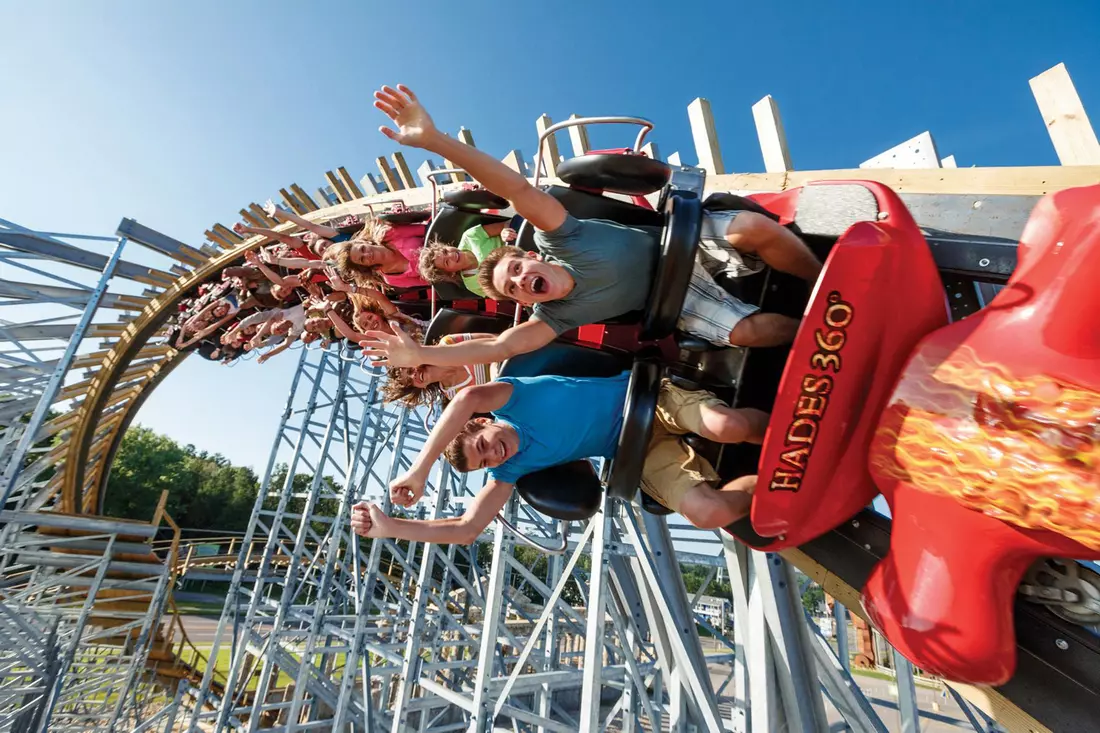 Thrilled riders on the Hades 360 roller coaster at an amusement park