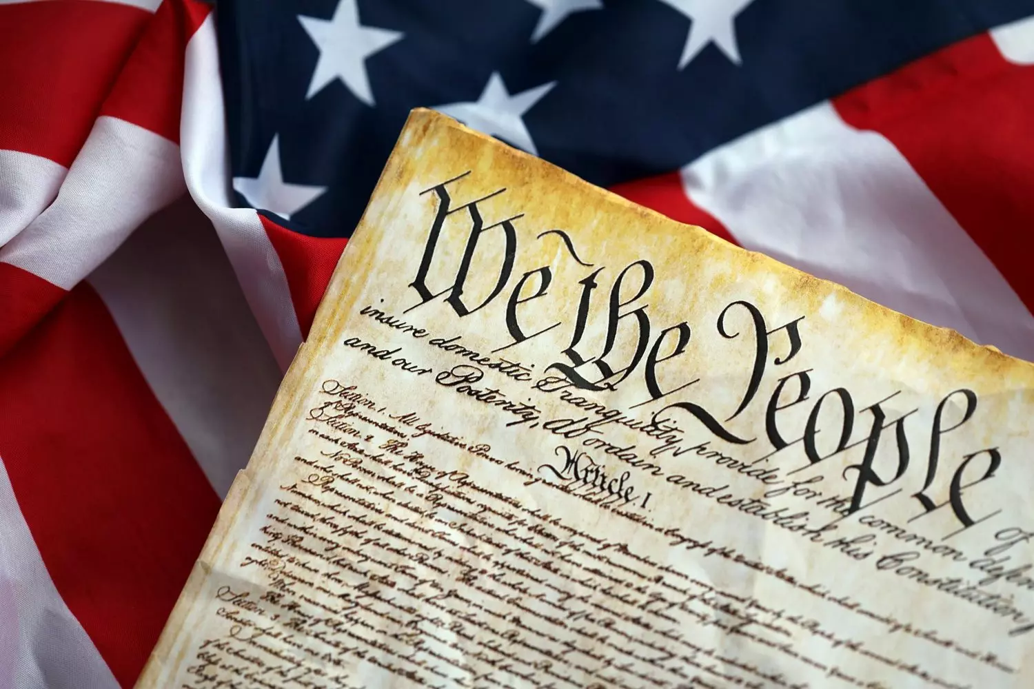 Historic Document: Page from the US Constitution with American Flag Photo of American history symbols: a handwritten page of the Constitution against a US national flag background