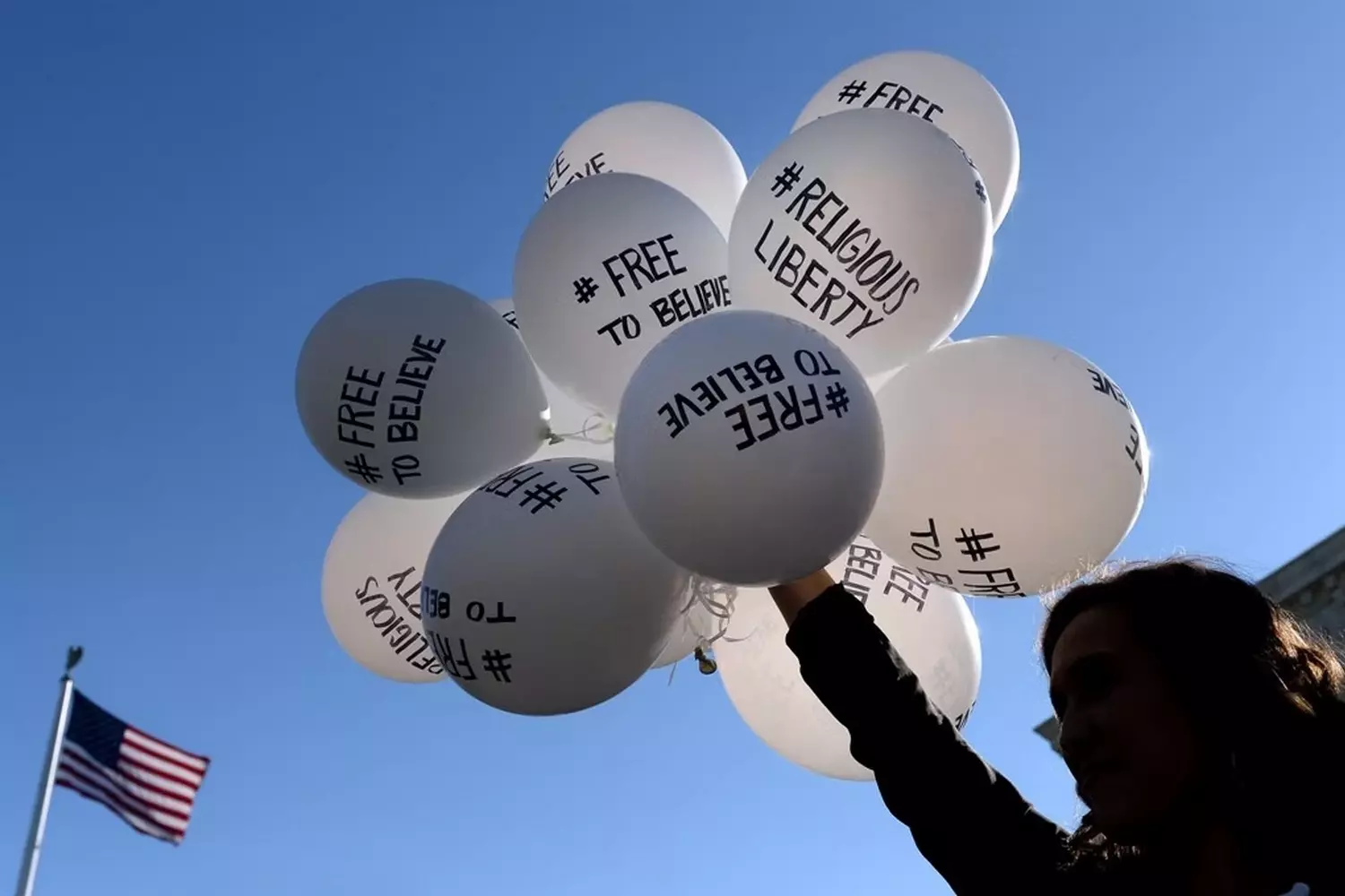 First Amendment concept: balloons representing religious freedom Close-up of a woman's hands holding strings of helium balloons featuring words like "Liberty" and "1st Amendment" alongside religious symbols