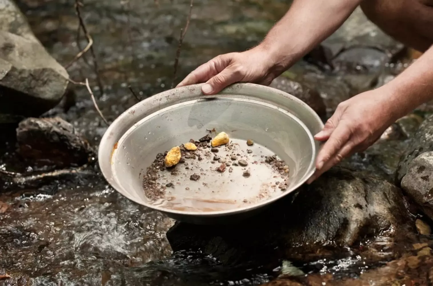 Gold panning: the centuries-old technology of prospectors Close-up of hands panning for gold using a traditional pan: the process of separating gold flakes from river sand and gravel, replicating the historical method used by gold miners