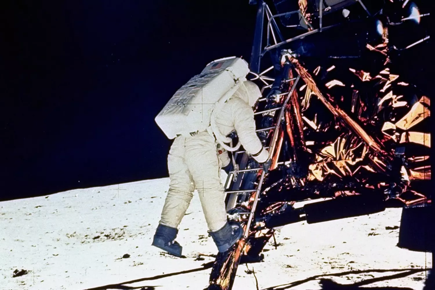 Один маленький шаг: астронавт на Луне — исторический момент миссии «Аполлон-11» Астронавт в белом скафандре стоит на лунной поверхности, в чёрном небе видна Земля