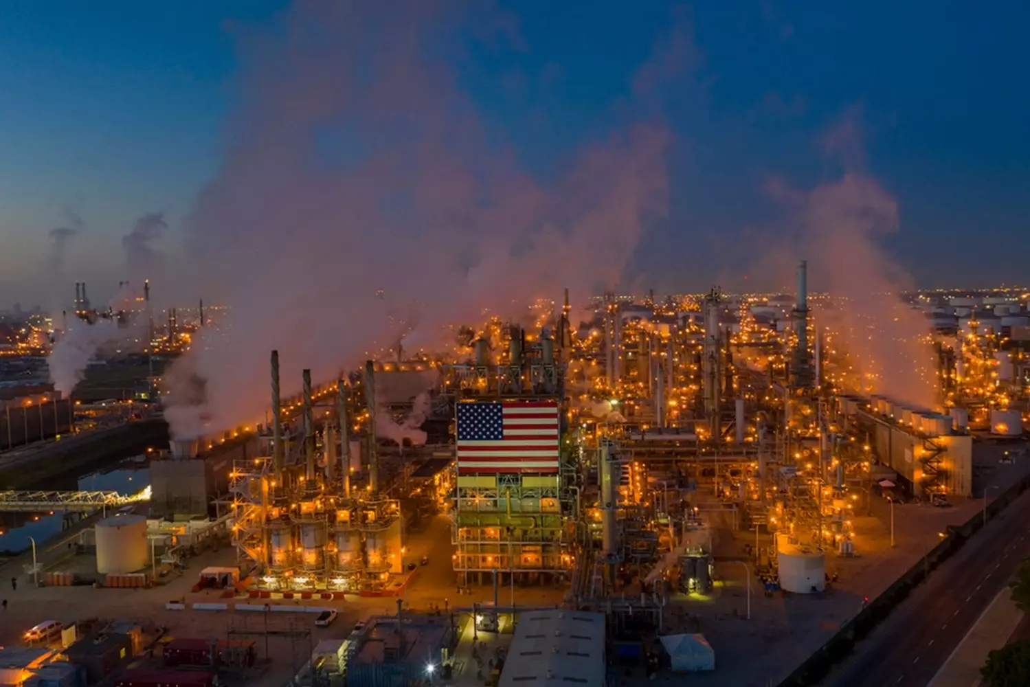 Смог над нефтезаводом в США: Экологическая цена энергетики Густой дым и смог, поднимающиеся из труб нефтеперерабатывающего завода в США — визуальное напоминание о воздействии промышленности на экологию