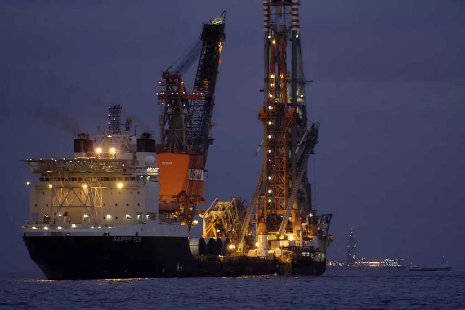 Морская добыча нефти в США: Энергия из глубин океана Крупная морская буровая платформа в территориальных водах США добывает нефть с океанского дна при поддержке вспомогательных судов