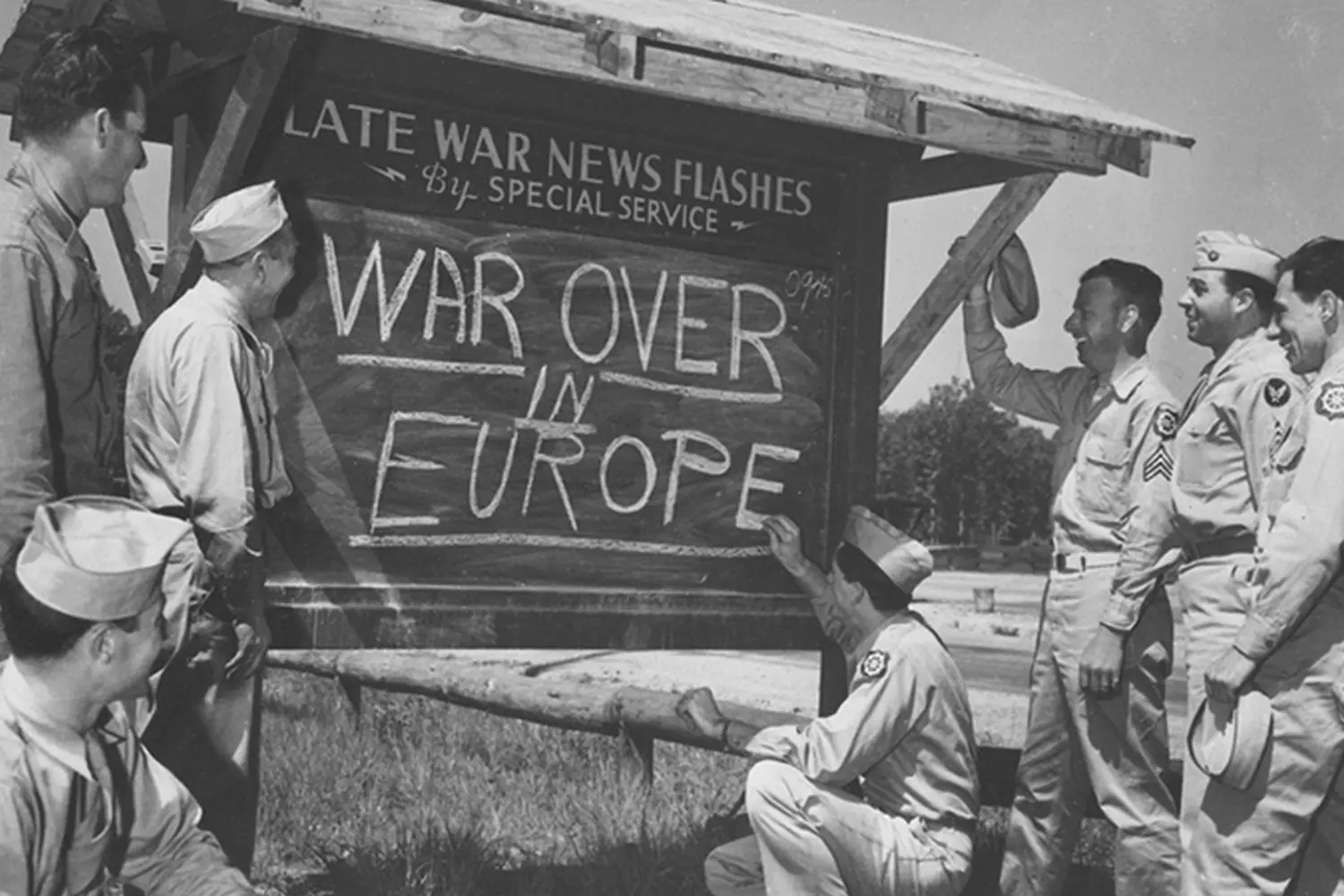 American Soldiers Celebrate Victory: Writing the News on a Blackboard A group of WWII American soldiers in field uniforms writing a victory message with chalk on a large blackboard