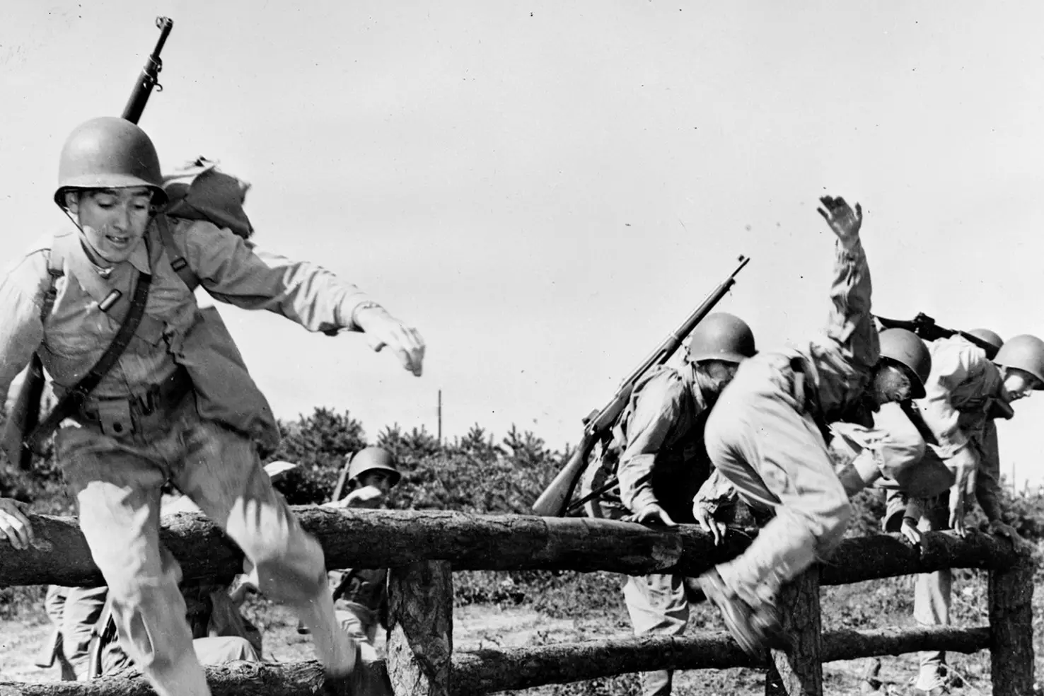 US Soldiers Overcoming Obstacles During WWII Training American infantrymen in full combat gear jumping over a wooden fence during field exercises
