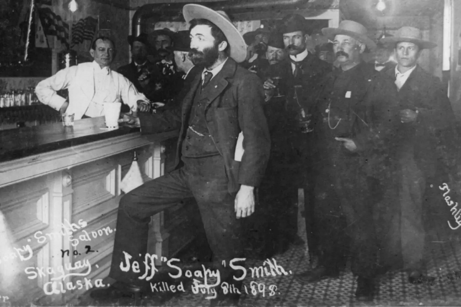 Cowboys in a Saloon: A Classic Scene from the Wild West A black and white historical photo of cowboys gathered inside a rustic saloon