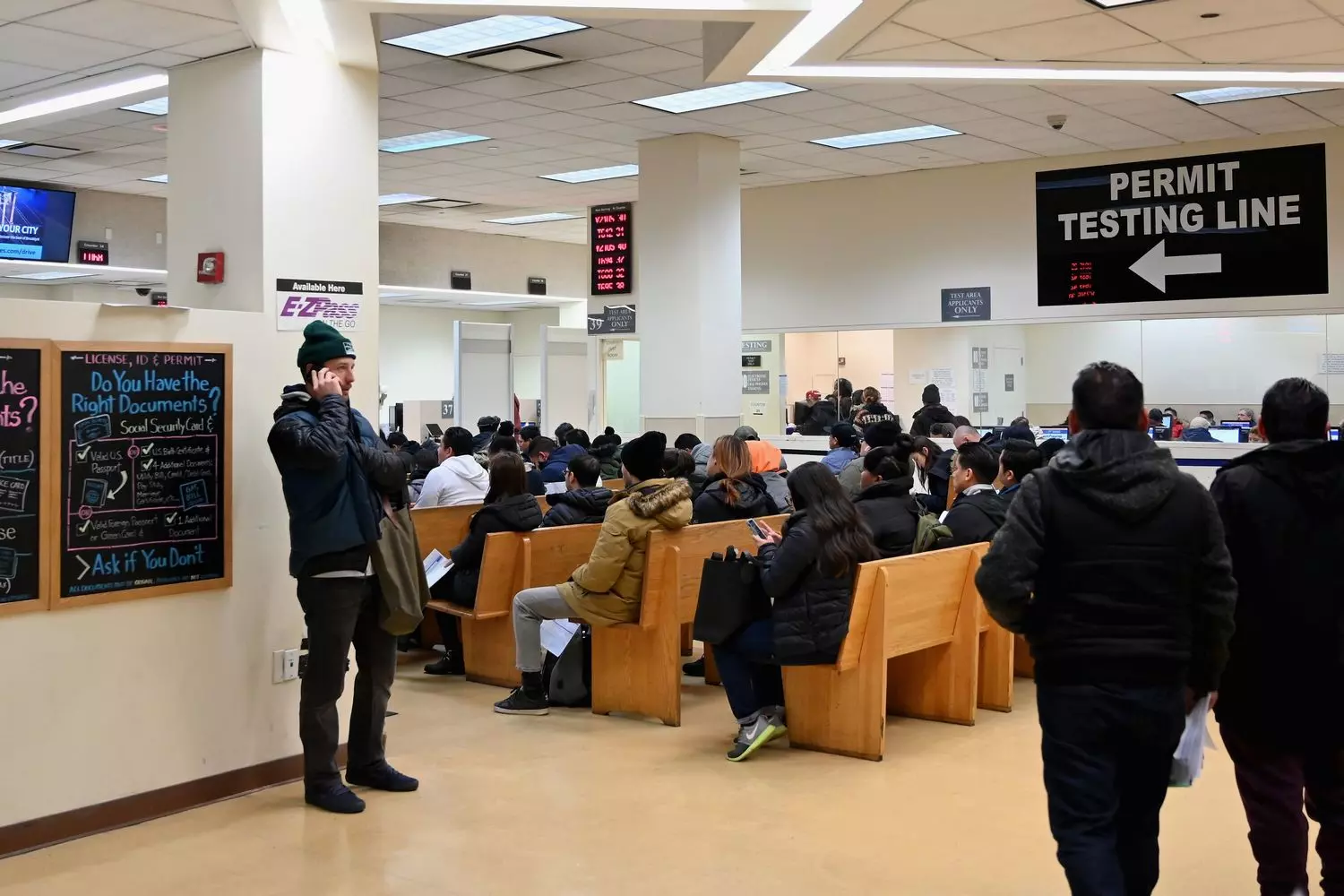 С чего начинаются права в США: первый визит в DMV Люди сидят в зале ожидания офиса DMV с документами в руках, готовясь к получению водительских прав