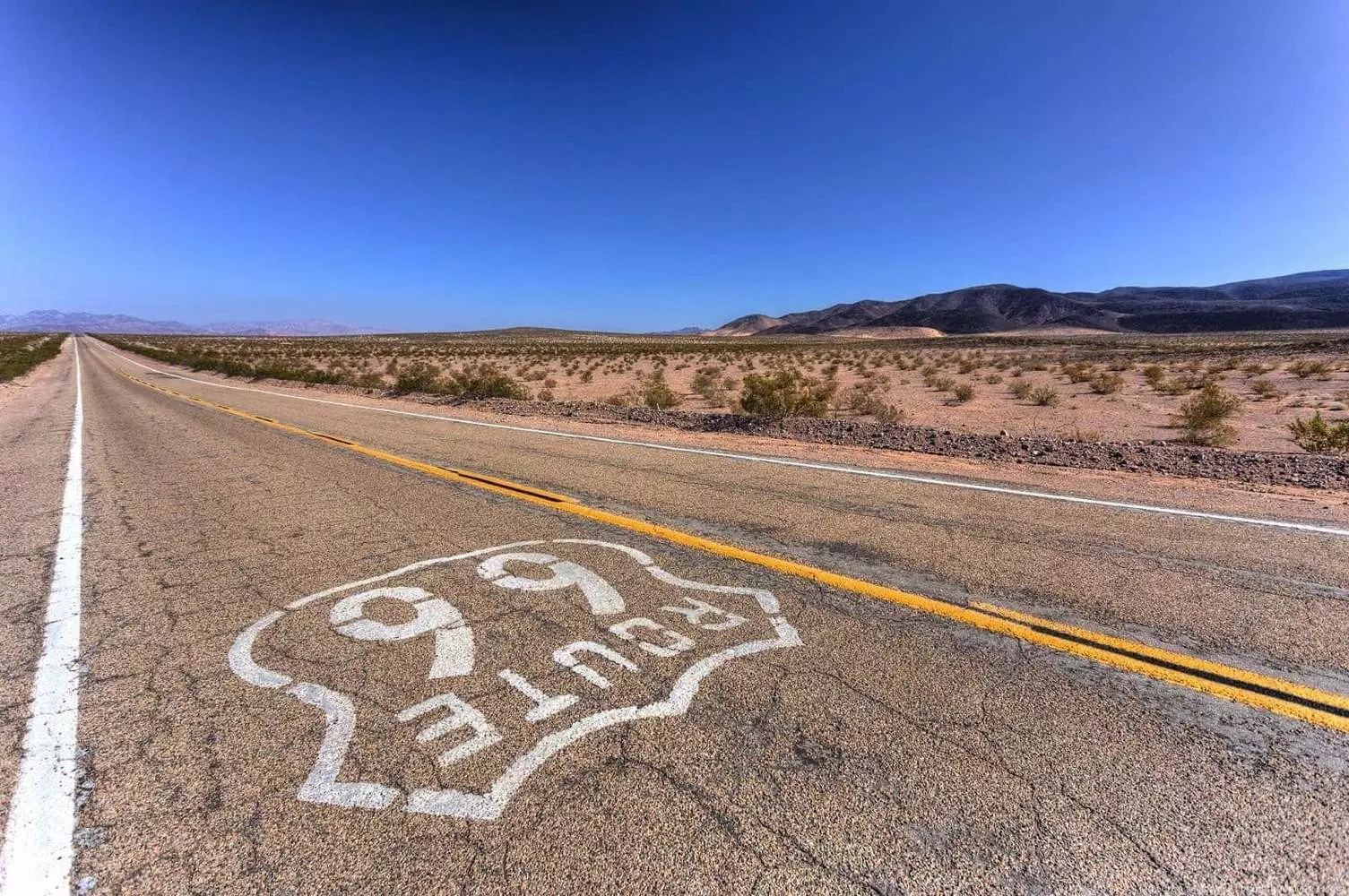 Мать Дорог: путешествие по легендарному шоссе 66 Классический вид на шоссе 66 в США, уходящее к горизонту через пустынный пейзаж