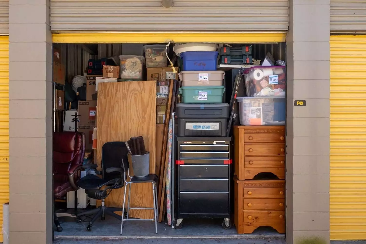 Loaded storage unit in the USA: efficient space organization for personal belongings Fully packed storage unit in the USA containing stacked boxes, chairs and household belongings