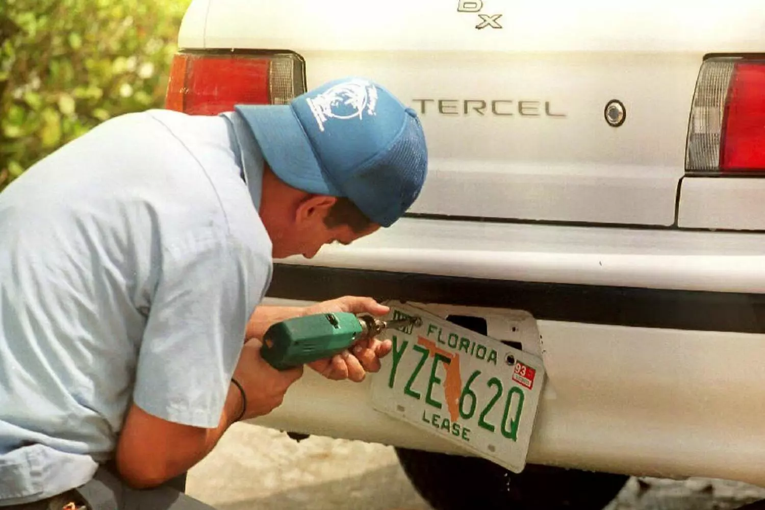 Улыбающийся мужчина с гордостью устанавливает свой новый персональный номерной знак