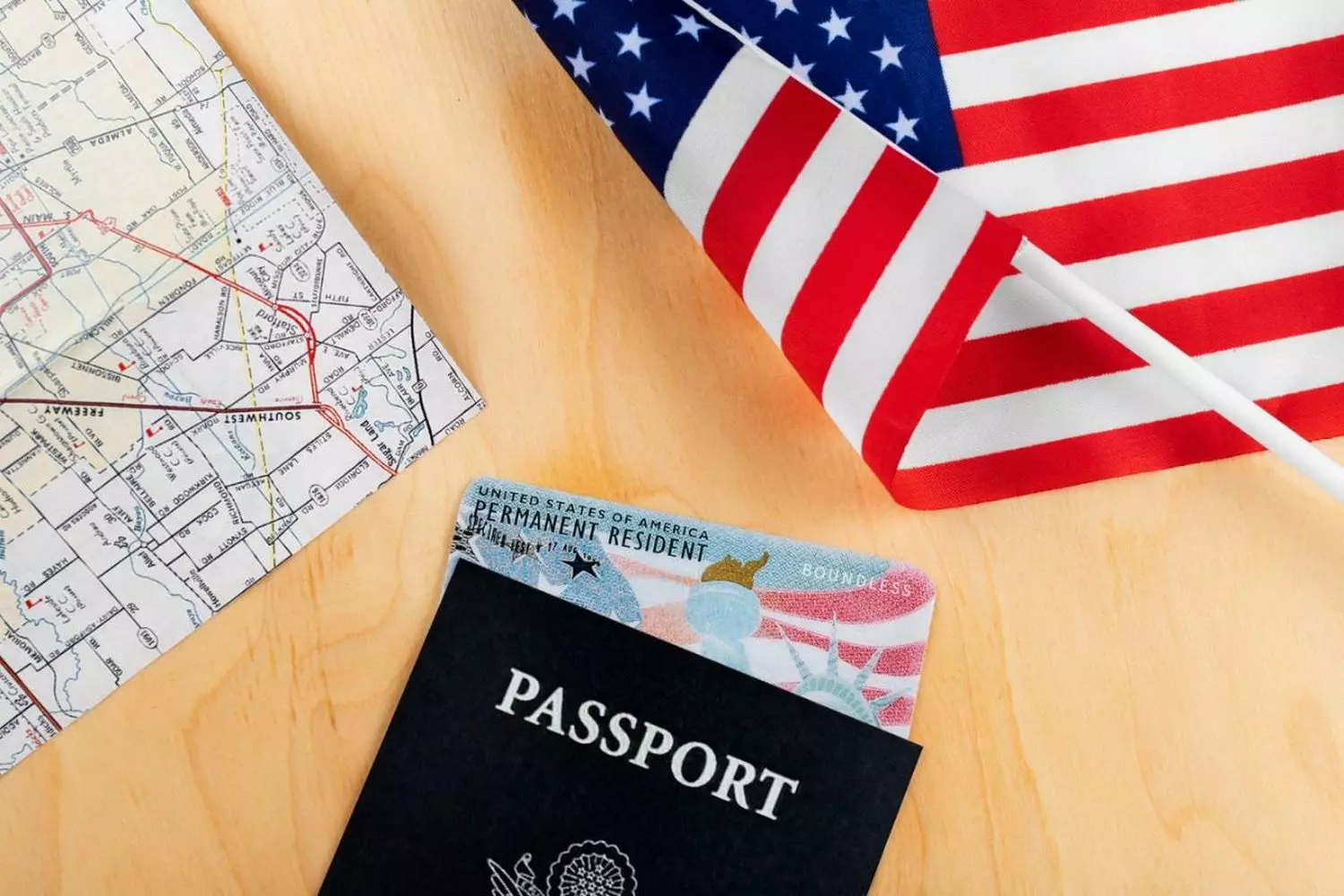 Американская мечта: флаг США, грин-карта и паспорт Символическая композиция с американским флагом, грин-картой постоянного резидента и паспортом США на деревянном фоне, олицетворяющая иммиграцию и гражданство