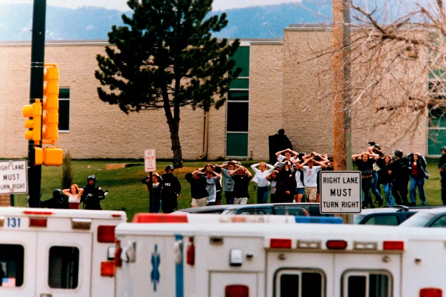 Terror in the Hallways: Students Flee Columbine High During 1999 Mass Shooting Black-and-white photo of Columbine High students walking single file with hands on their heads as police escort them to safety during the April 20, 1999 school shooting